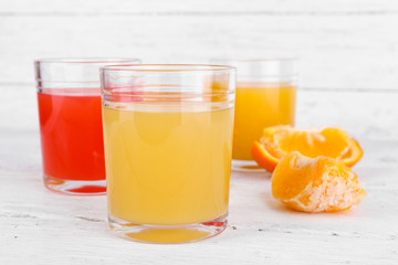 Different sliced citrus fruits and glasses of juice