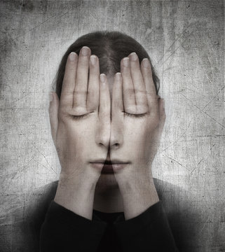 Woman covers her face with her hands on the grunge backround.  S