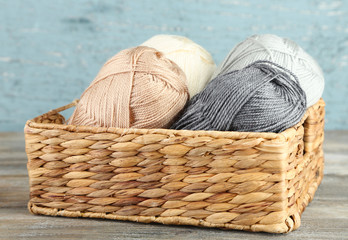 Knitting yarn in basket, on wooden background