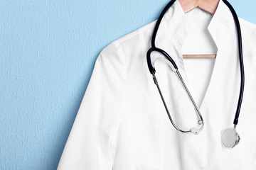 Doctor coat with stethoscope on hanger on blue background