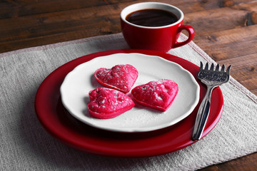 Cookies in form of heart in plate with cup of coffee