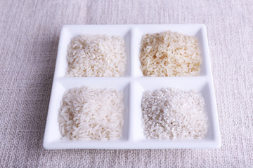 Different types of rice on plate on fabric background