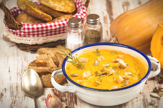 Homemade pumpkin soup in a tin bowl on rustic table