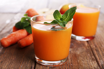 Glasses of juice with apple and carrot on wooden table close up