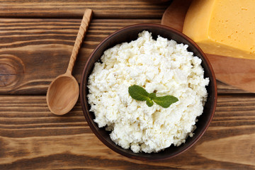 Cottage cheese in bowl with cheese on wooden background