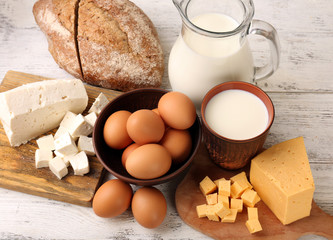 Tasty dairy products with bread on wooden table close up