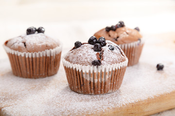 Delicious chocolate muffins on wooden board 