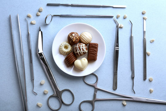 Dentist Tools With Sweets And Teeth On Light Background