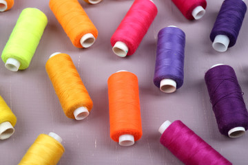 Multicolor sewing threads on wooden background