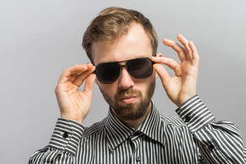 Naklejka premium Confident casual man taking off his dark shades and looking at you.