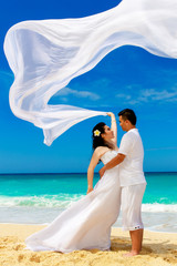Fototapeta na wymiar Asian bride and groom on a tropical beach. Wedding and honeymoon