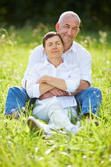 Fototapeta premium Paar Senioren sitzt entspannt auf einer Wiese