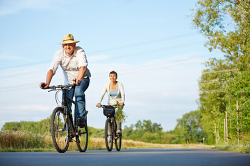 Senioren fahren mit Fahrrad durch Landschaft