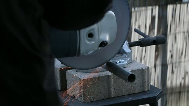 Handwerker trennt Eisenrohr mit Winkelschleifer