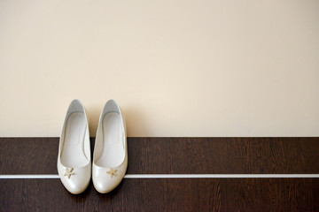 White shoes of bride clings to the edge bed