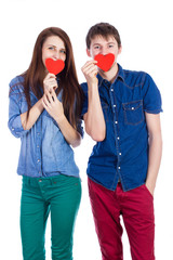 Beautiful young couple holding a small red paper heart in hands