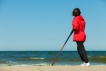 Nordic walking. Woman hiking on the beach.