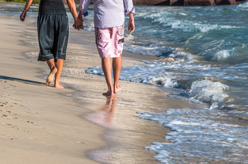 Couple in love holding hands and walking on beach in winter