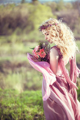 Peautiful blonde girl in a pink dress with a bouquet of flowers