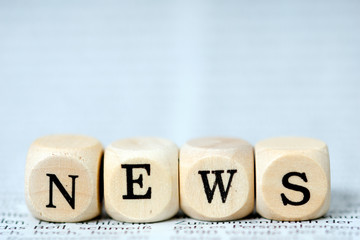 Holzwürfel mit dem Wort News auf einer Zeitung