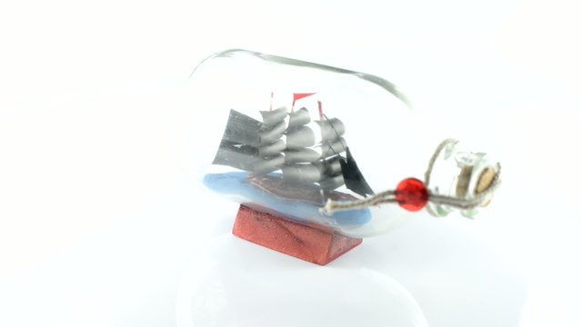 Old sailboat in glass bottle on a white background, the rotation around the axis
