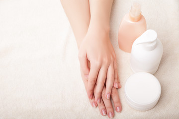 Woman's beautiful hands with care cream bottles