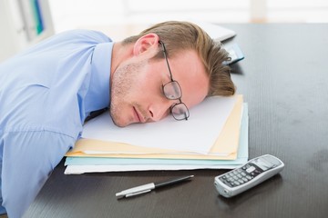 Tired businessman with stack of files on desk