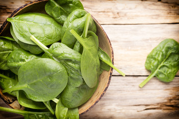 Spinach on the bowl, wooden background.