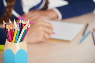 Close up photo of cup with pencils and schoolgirl