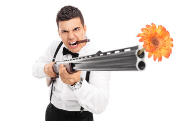 Fototapeta na wymiar Angry guy shooting flowers from a rifle