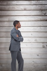 Composite image of businessman standing with arms crossed