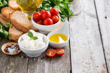 mozzarella and ingredients for the salad on a wooden background