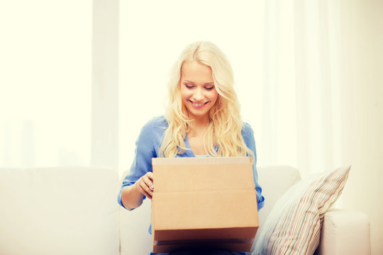 smiling young woman opening cardboard box