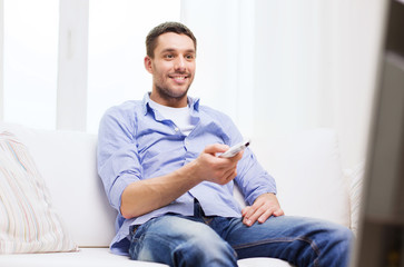 smiling man with tv remote control at home