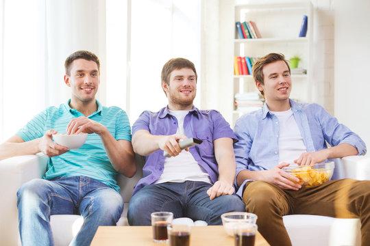 happy male friends watching tv at home