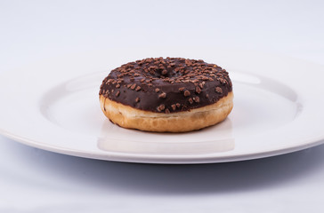 Chocolate glazed donut on white plate