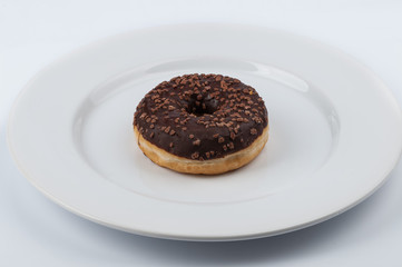Chocolate glazed ring donut on white plate