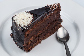 A slice of chocolate cake with chocolate glossy syrup topping an