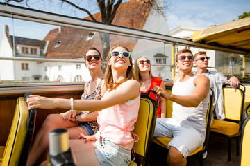 group of smiling friends traveling by tour bus
