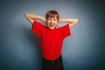 Fototapeta premium boy teenager European appearance in a red shirt covered his ears