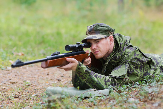 young soldier or hunter with gun in forest