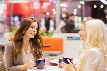 smiling young women drinking coffee in mall