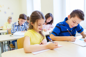 group of school kids writing test in classroom