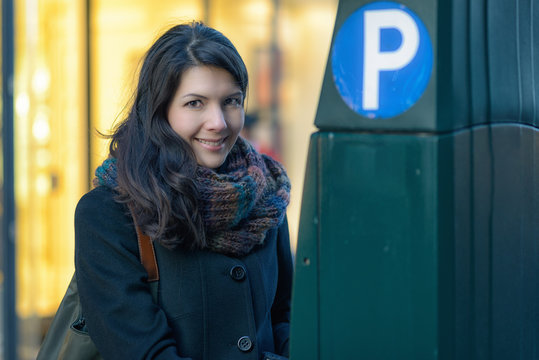 Attraktive Frau bezahlt an einem Parkscheinautomaten