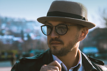 Glamour portrait of beauty man in hat and glasses looking away o