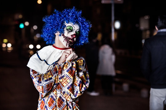 Crazy ugly grunge evil clown on Halloween making people scared