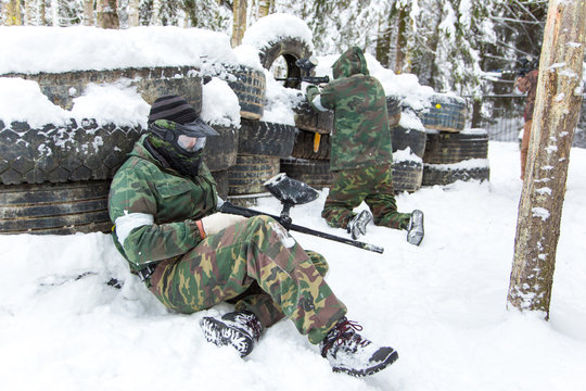Two men defending tire paintball fortification covered with snow