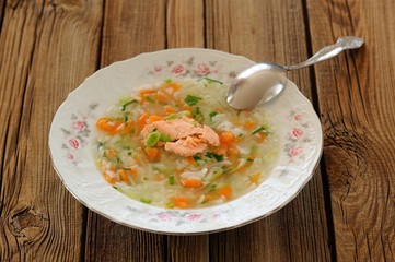 Homemade fish soup with rice and carrot on wooden background