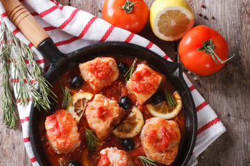 fish in tomato in a pan and ingredients horizontal top view