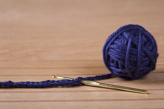 Ball of blue yarn with crochet needle